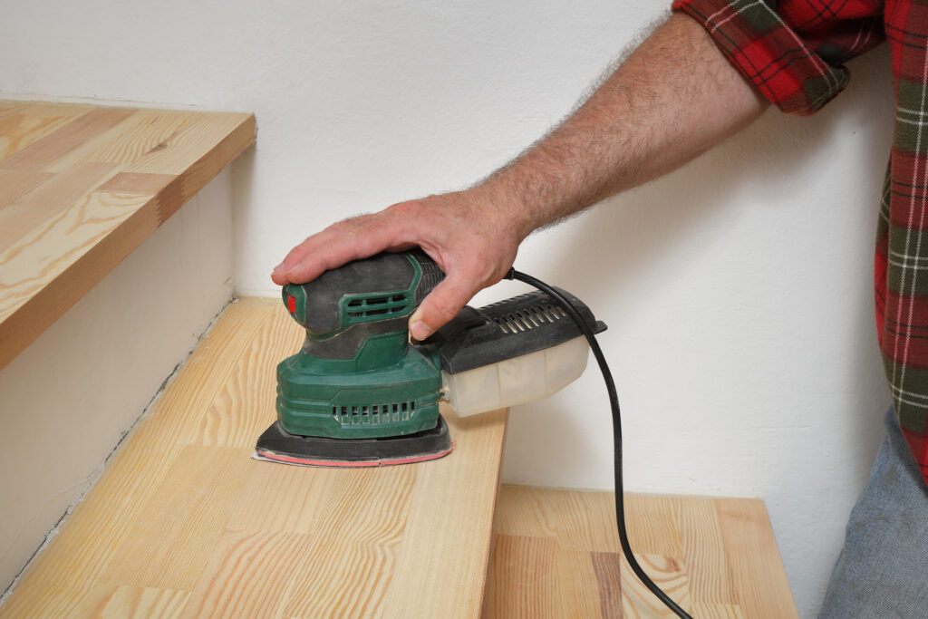 a diyer sanding the surface of their stair treads