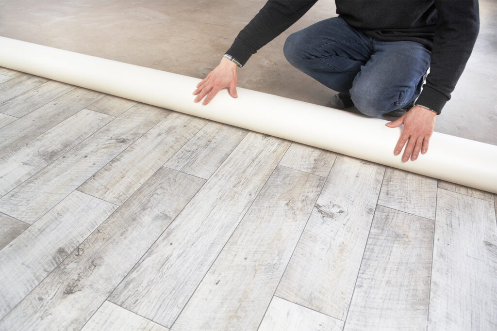 a flooring fitter laying vinyl flooring in a living room