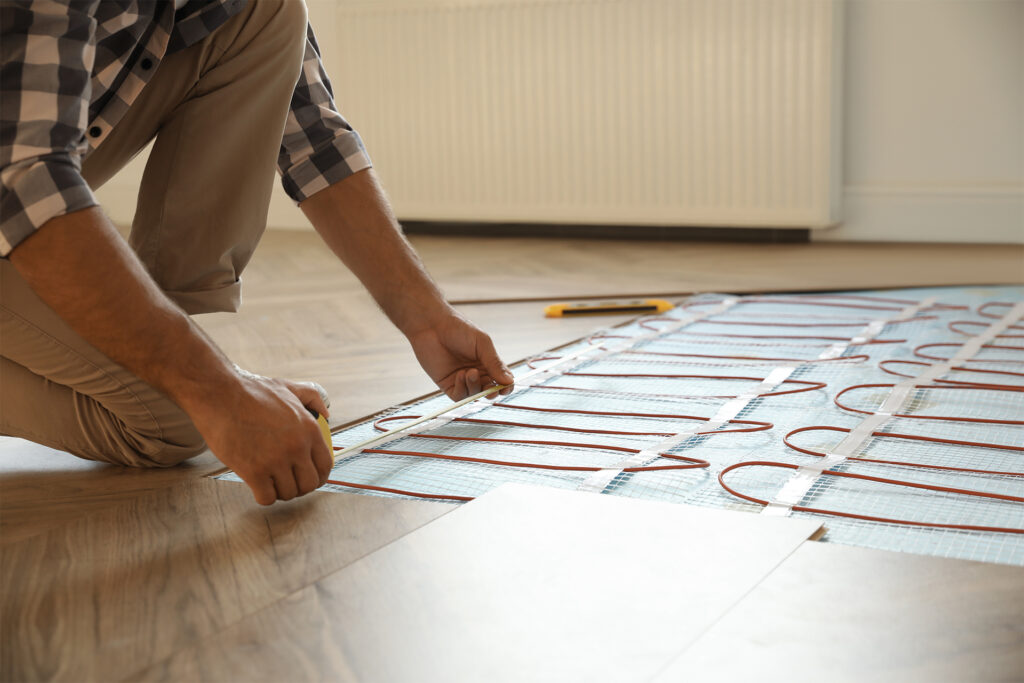 a homeowner doing a DIY installation of wood flooring over underfloor heating