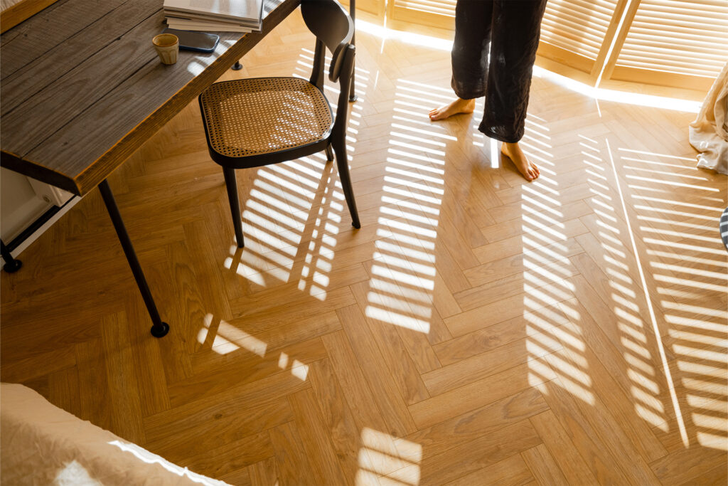 a homeowner standing barefoot on herringbone flooring in a sparse office