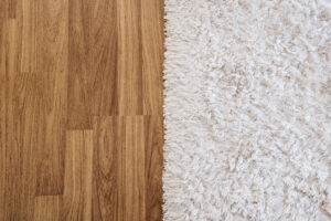 a close up of wood floors versus carpet, each taking up half of the screen